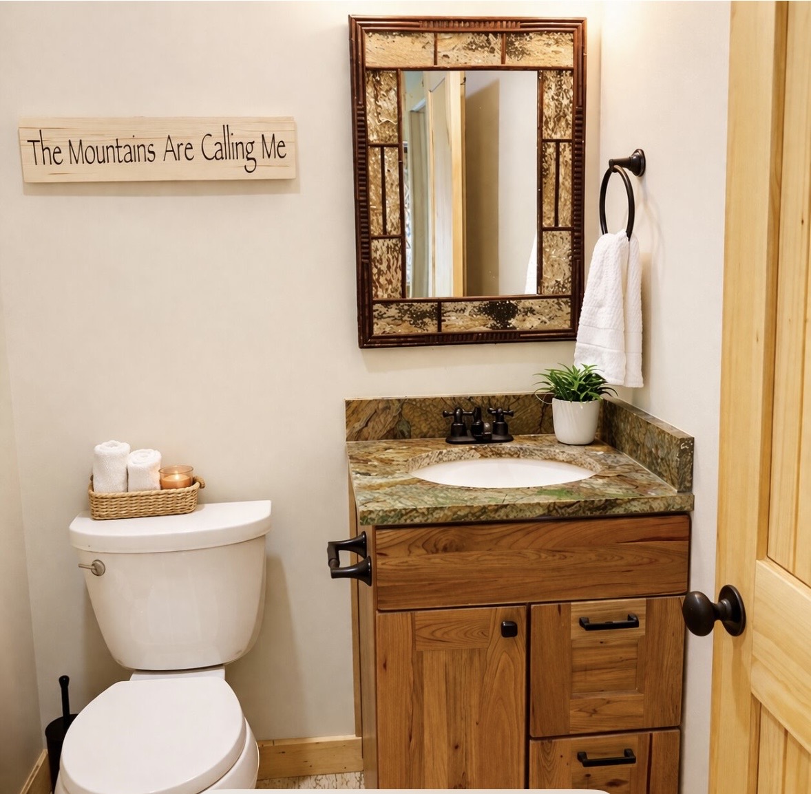 Bathroom vanity with mosaic mirror and mountain-themed sign
