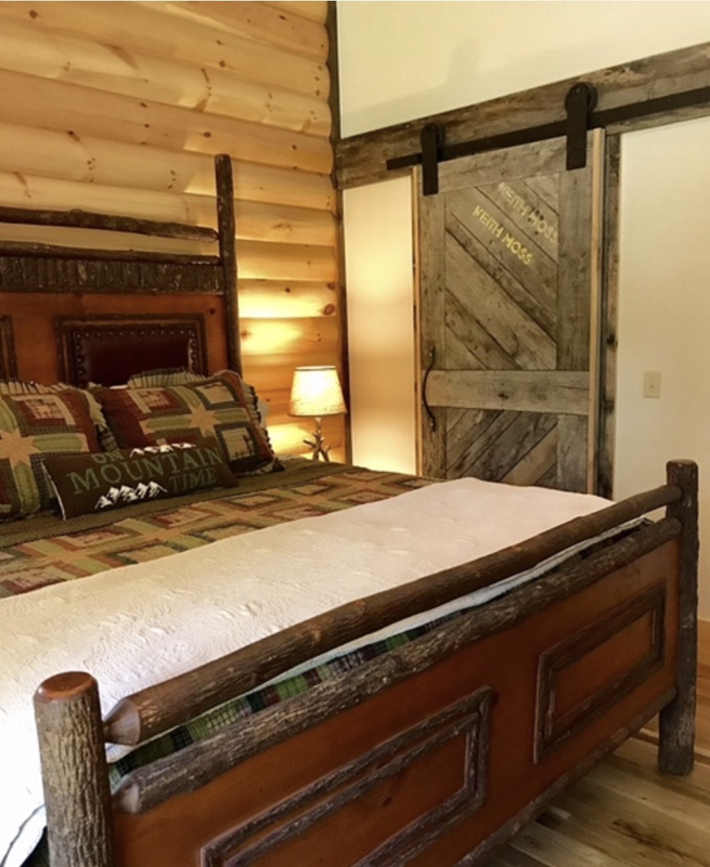 King bedroom with log bed frame and sliding barn door
