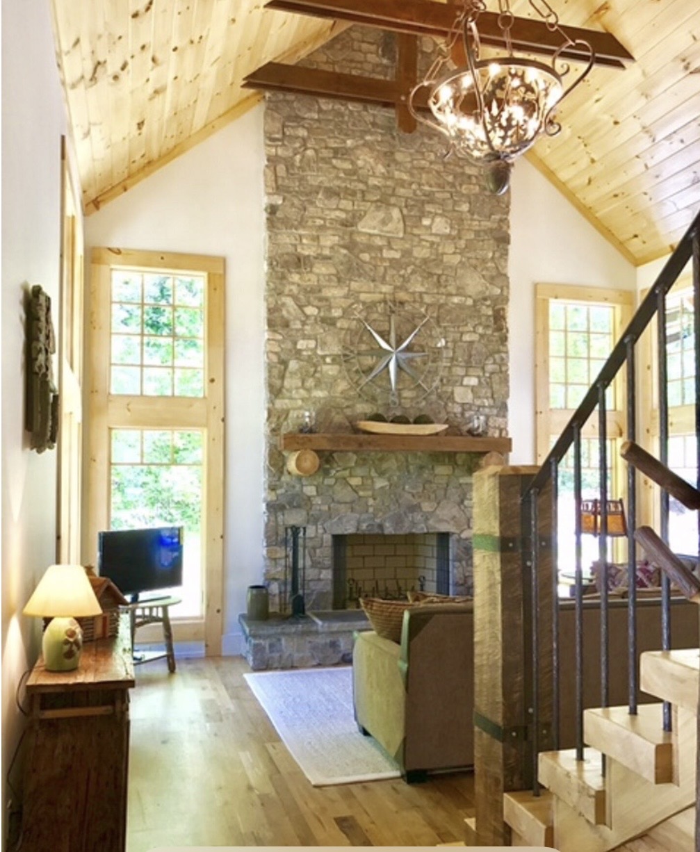 Living room with tall stone fireplace and floor-to-ceiling windows
