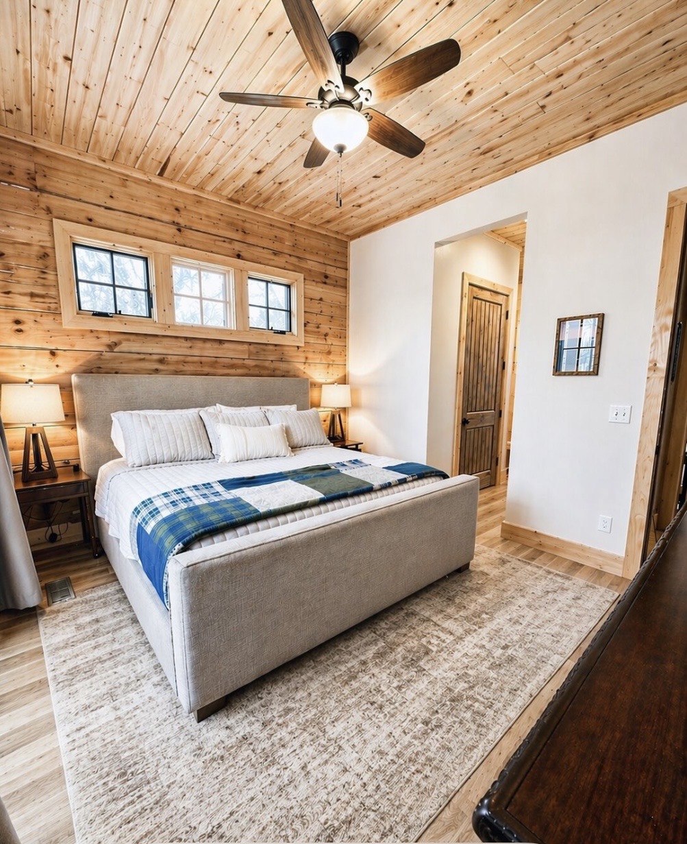 King bedroom with upholstered bed and wood ceiling fan