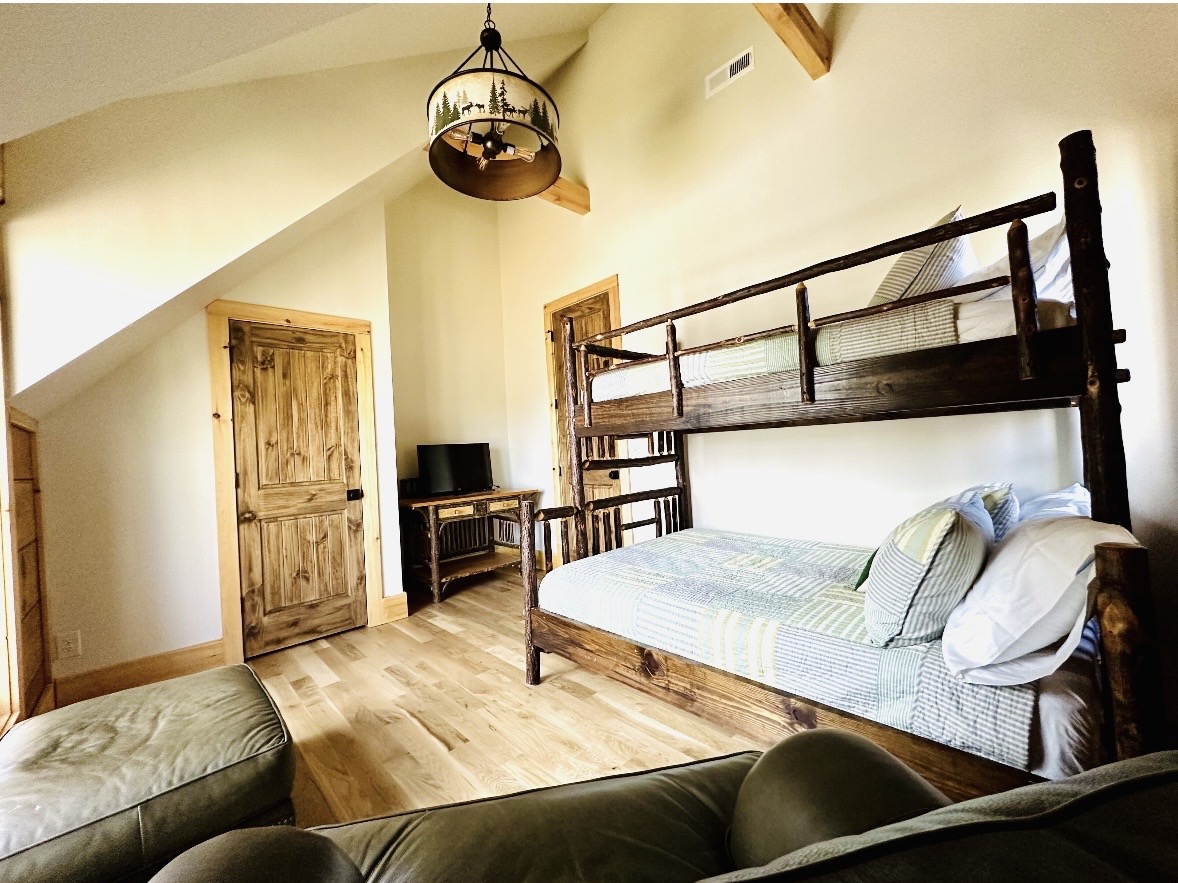 Bunk room with rustic log-frame bunk bed