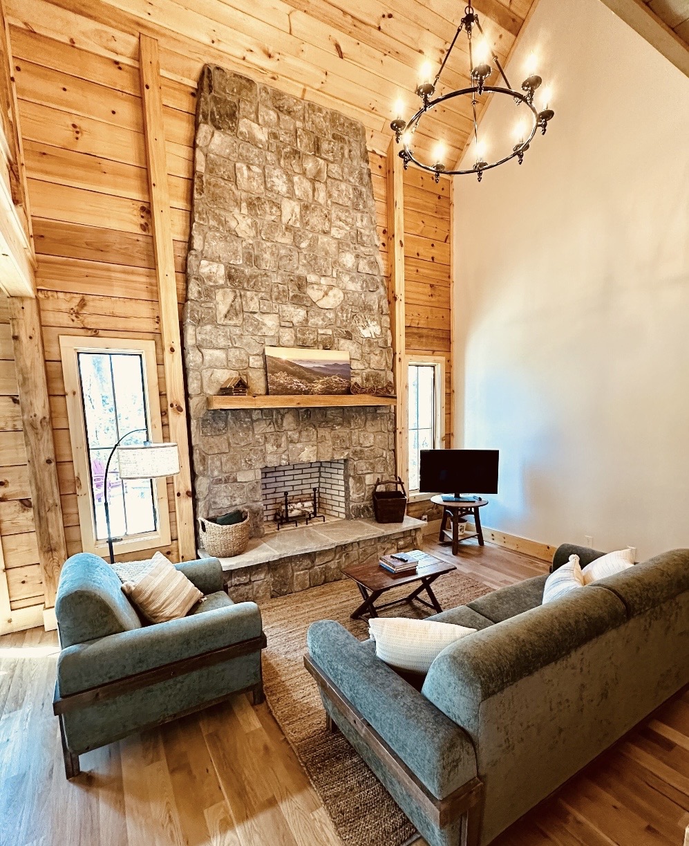 Vaulted living room with tall stone fireplace and chandelier