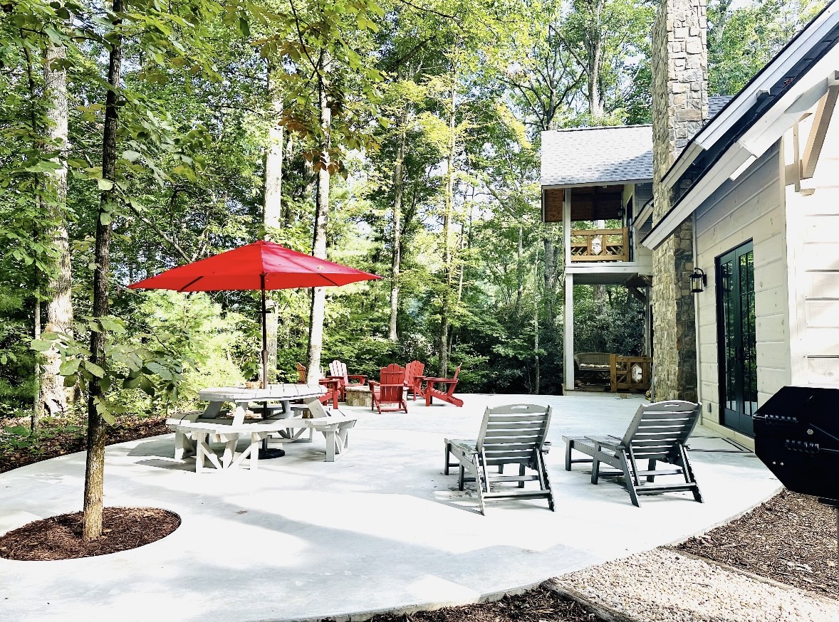 Patio with picnic table, red umbrella, and lounge chairs